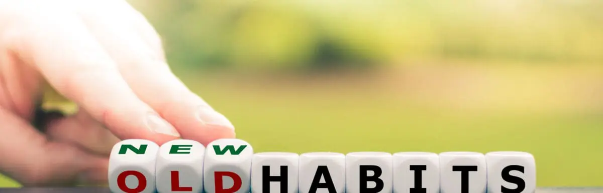 Hand flipping letter blocks to change the word “old habits” to “new habits,” symbolizing behavior change and habit formation