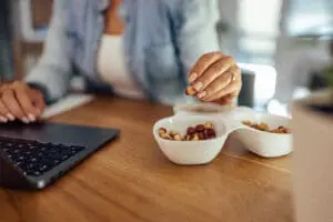 woman snacking on mixed nuts while working on her computer