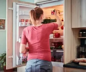 woman standing in front of open fridge door