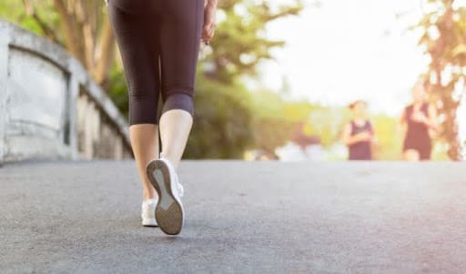 Women in athletic clothes are exercising outside.