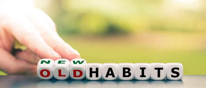 Hand flipping letter blocks to change the word “old habits” to “new habits,” symbolizing behavior change and habit formation