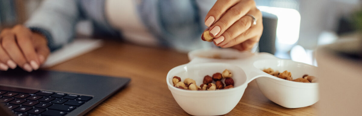 woman snacking on mixed nuts while working on her computer