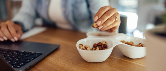 woman snacking on mixed nuts while working on her computer