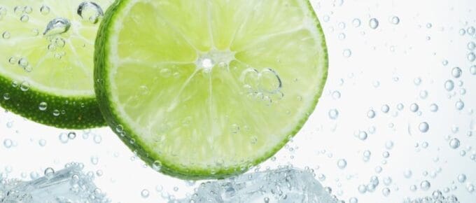 clear drink with bubbles, ice, and lime slices