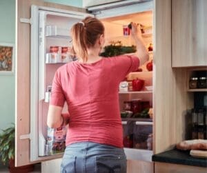 woman standing in front of open fridge door